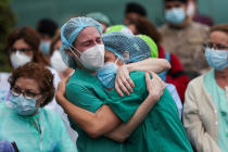 Dos enfermeras se abrazan ante una multitud de sanitarios